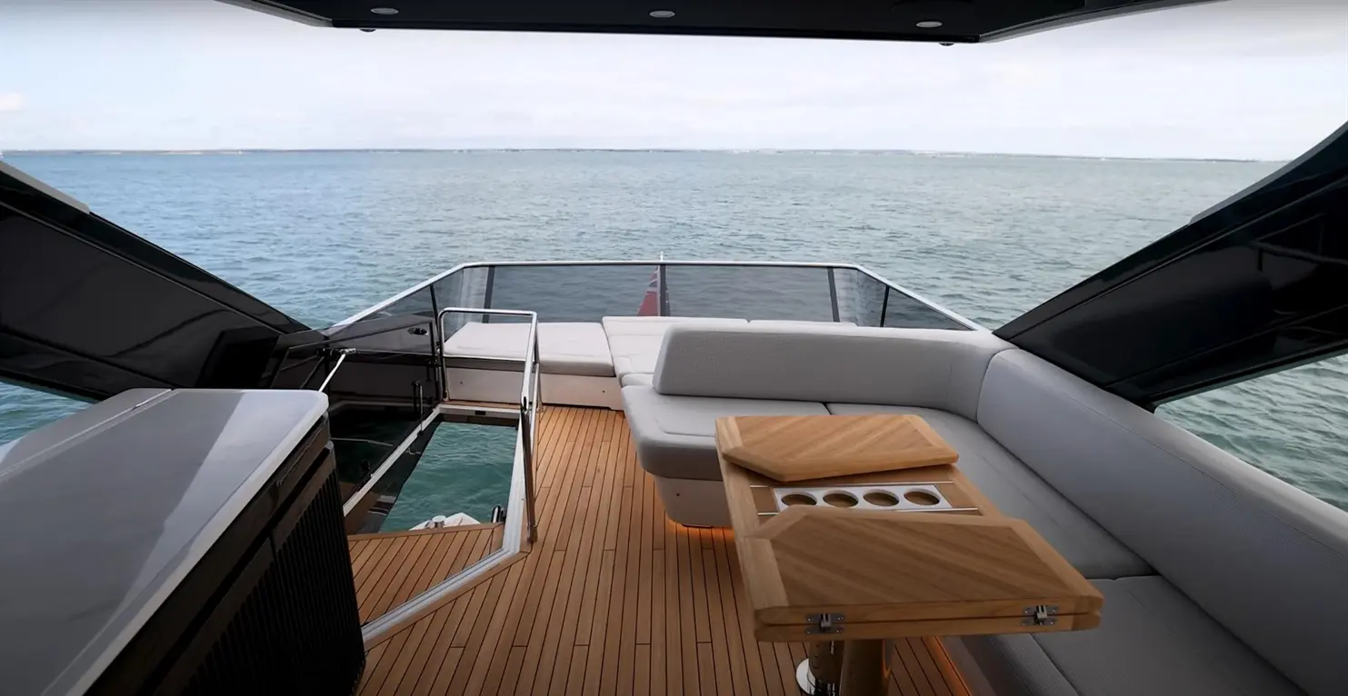 Luxury yacht deck featuring a stylish seating area, wooden table, and panoramic views of the calm sea.